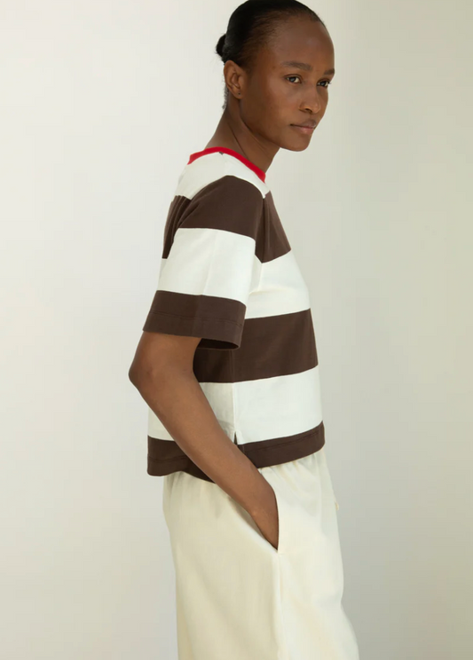 Person wearing a brown and white striped shirt with a red collar against a plain background