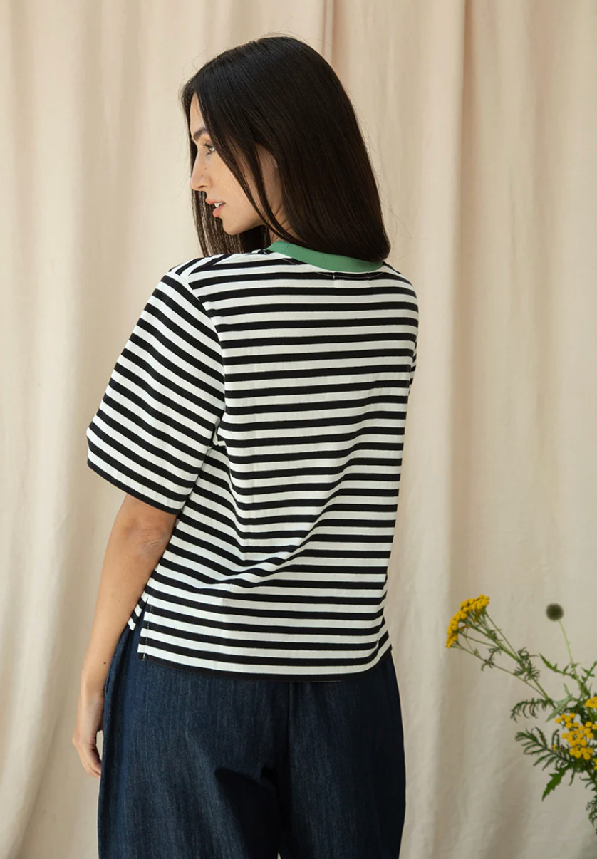 Woman wearing a black and white striped shirt with a beige curtain background