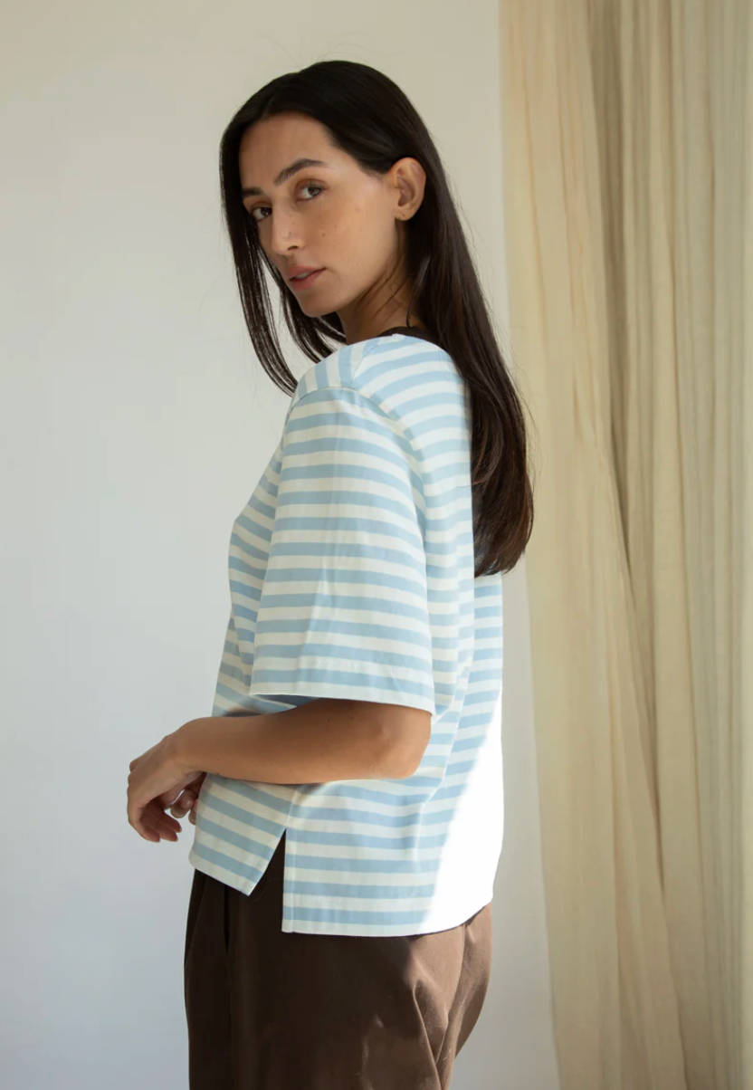 Woman wearing a light blue and white striped shirt against a neutral background