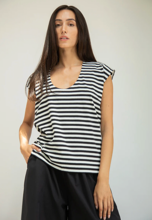 Woman wearing a black and white striped sleeveless top against a plain background