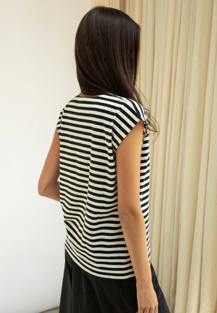Person wearing a black and white striped sleeveless top against a neutral background