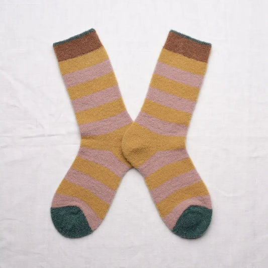 A pair of fluffy striped crew socks in an X shape on a white background. The sock stripes are a muted pink and yellow with brown and green cuffs and green toes.
