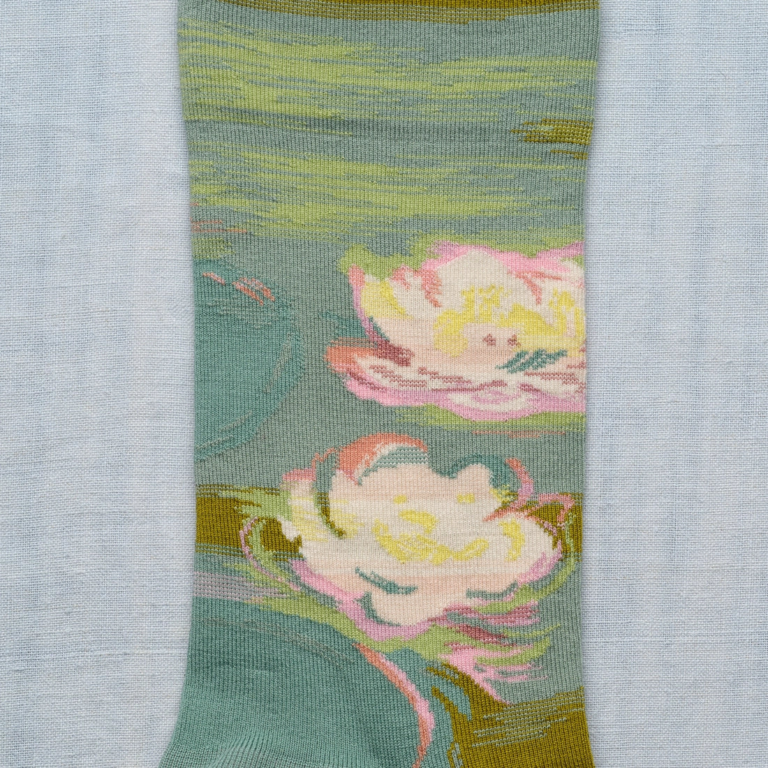 A closeup on a green sock with a Monet water lily design.