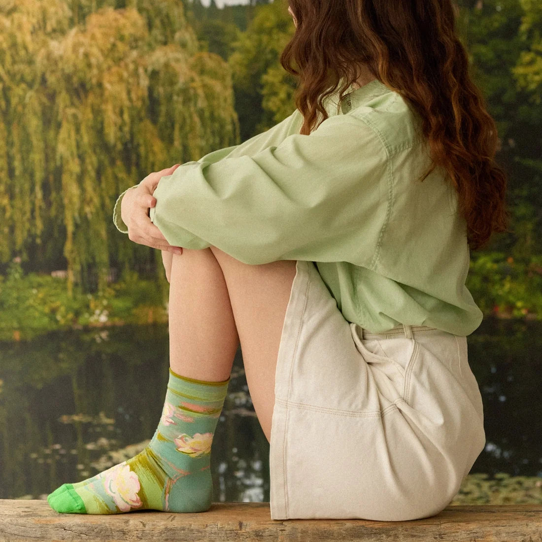 A model wearing a pair of green socks with a Monet water lily design and green toes.