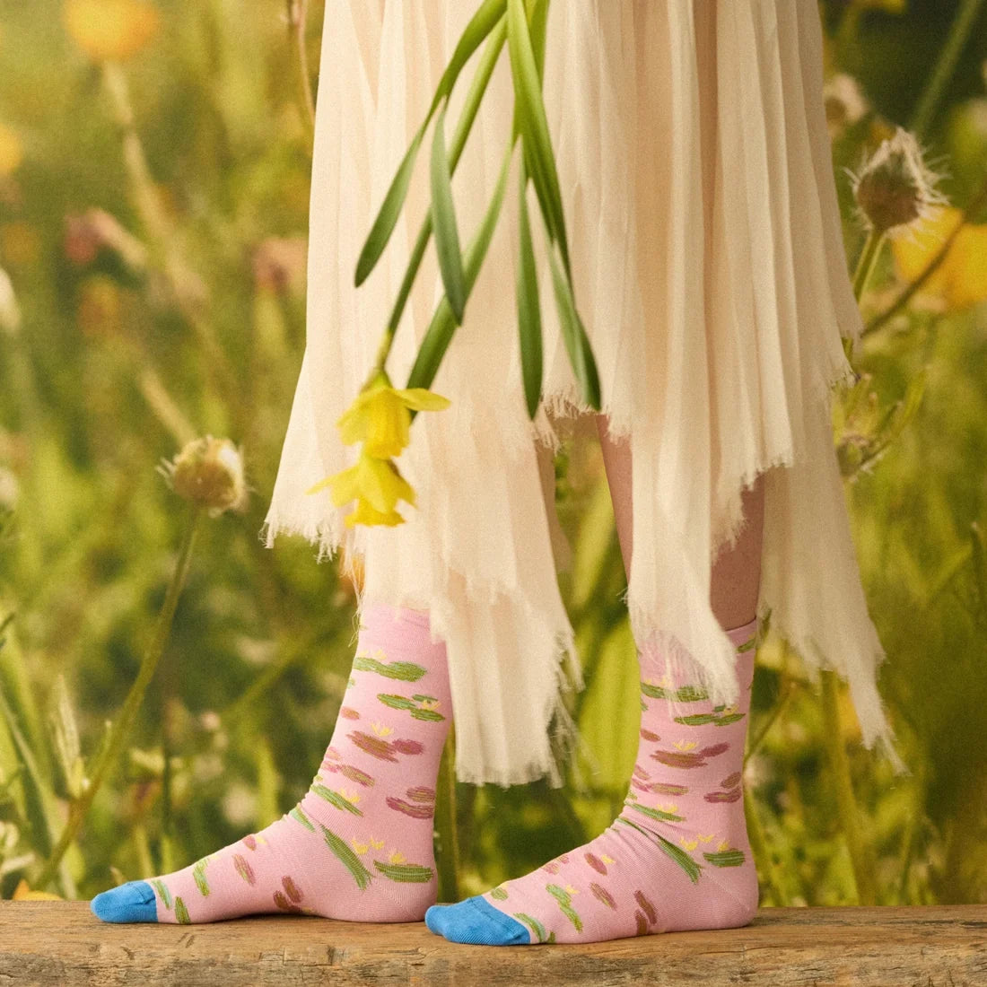 A model with flowers wearing a pair of pink socks with a monet water lily design and blue toes.