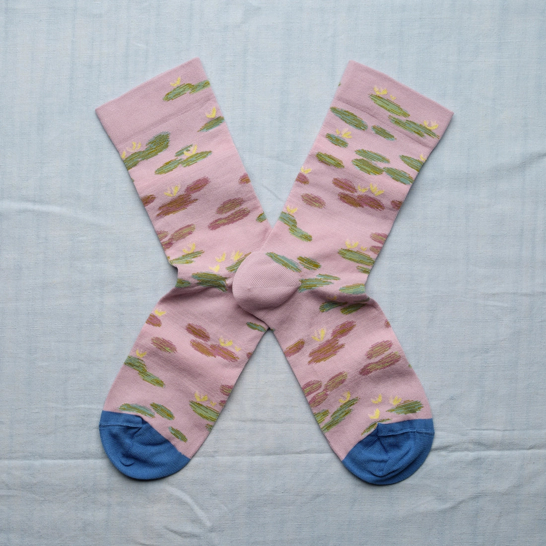 A pair of pink socks with a monet water lily design and blue toes.