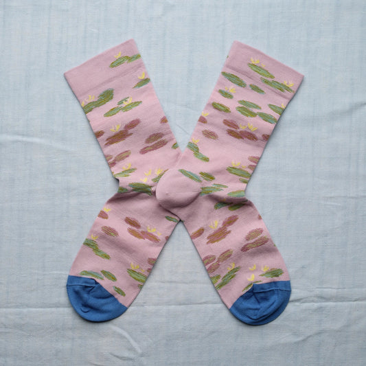 A pair of pink socks with a monet water lily design and blue toes.