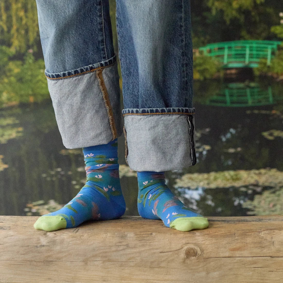 A model wearing a pair of blue socks with a monet water lily design and light green toes.