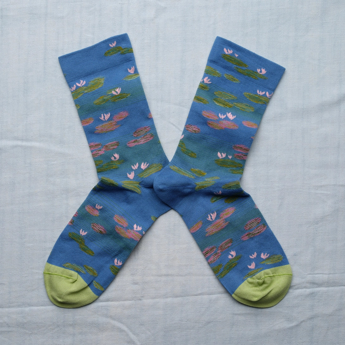 A pair of blue socks with a monet water lily design and light green toes.