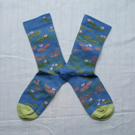 A pair of blue socks with a monet water lily design and light green toes.