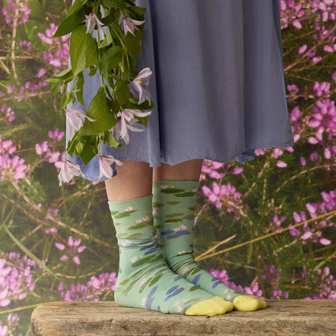 A model with flowers wearing a pair of green socks with a monet water lily design and yellow toes.