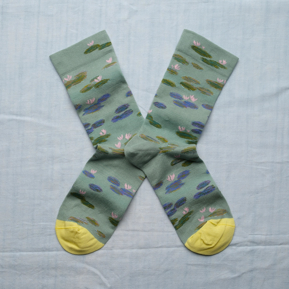 A pair of green socks with a monet water lily design and yellow toes.
