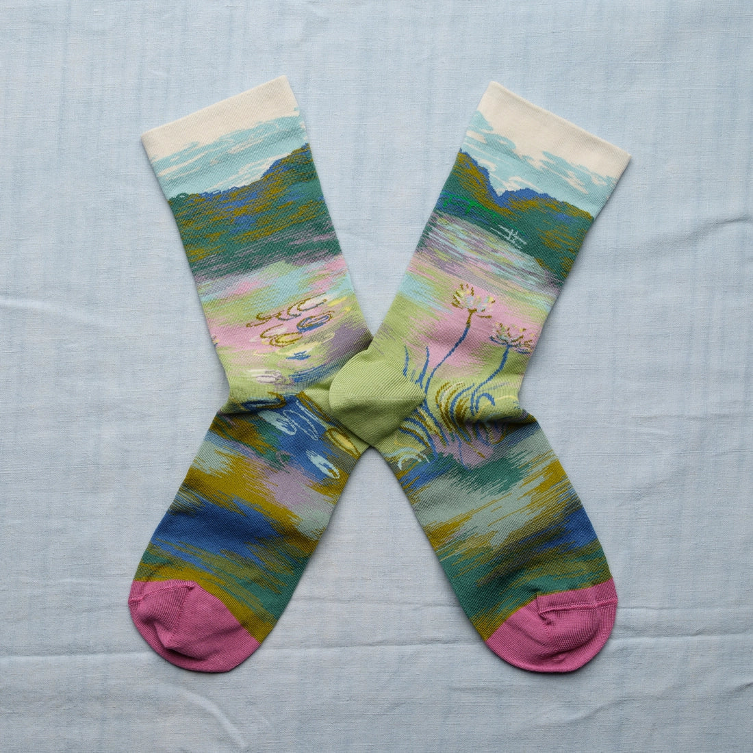 A pair of multicolor socks with a Monet bridge and water design and pink toes.