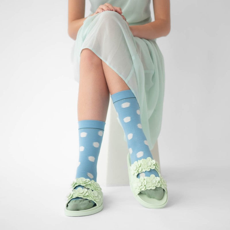 person wearing pair of mid blue socks with white polka dots and greet toe detail with pale green sandals