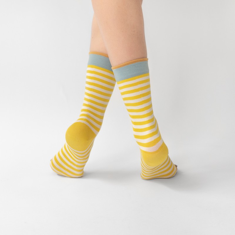 detail of person wearing pair of yellow and white striped socks with blue trim