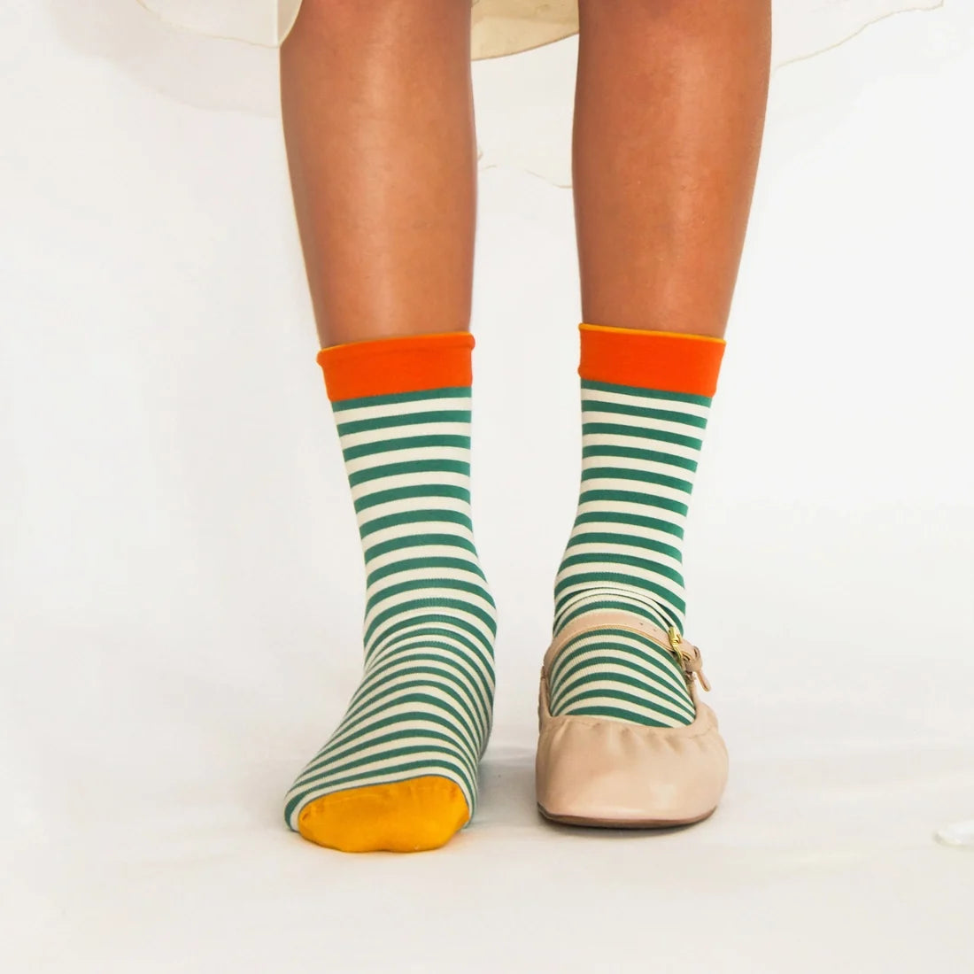 A model wearing pair of striped socks with green, orange, and yellow.