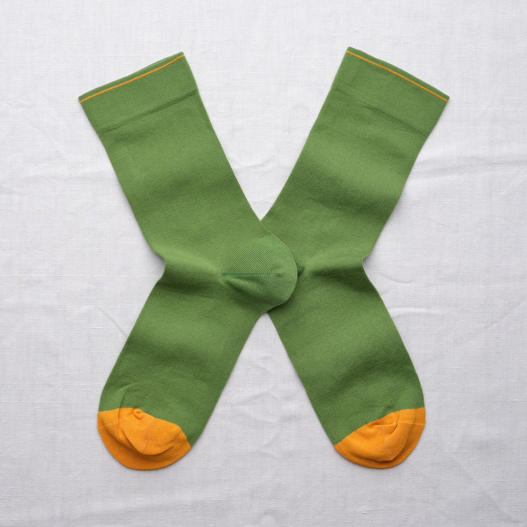Green socks with yellow toes and cuffs on a light gray background.