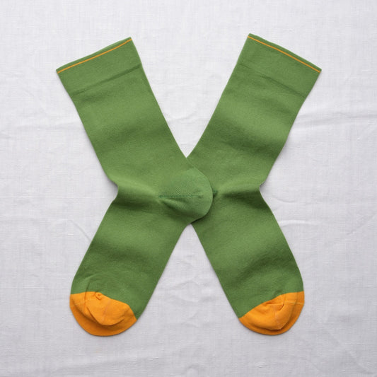 Green socks with yellow toes and cuffs on a light gray background.
