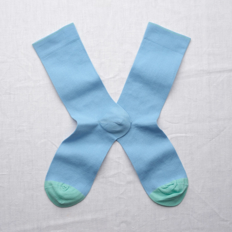 Light blue socks with green toes and heels on a white background
