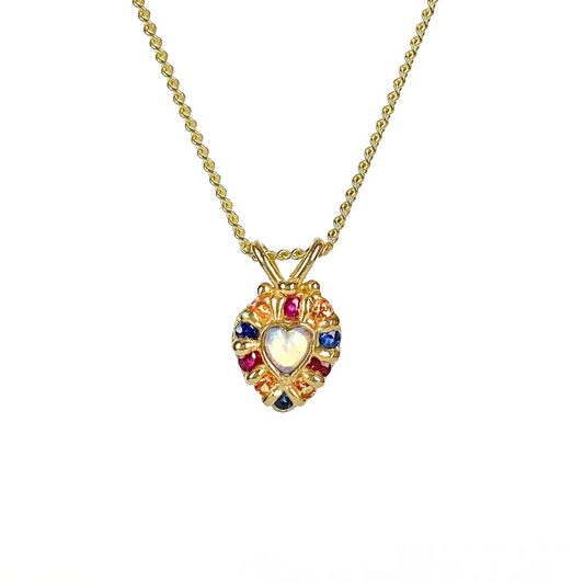 Small gold heart shaped pendant with heart shaped opal surrounded by sapphires and rubies on a gold chain