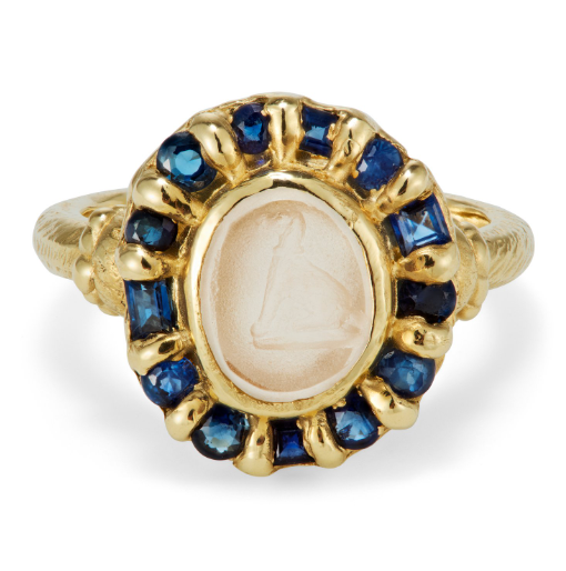 Oval shaped gold ring with antique agate intaglio with dog motif surrounded blue sapphires.