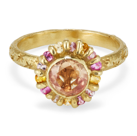 Gold ring with peach color sapphire surrounded by smaller yellow, pink and orange sapphires.