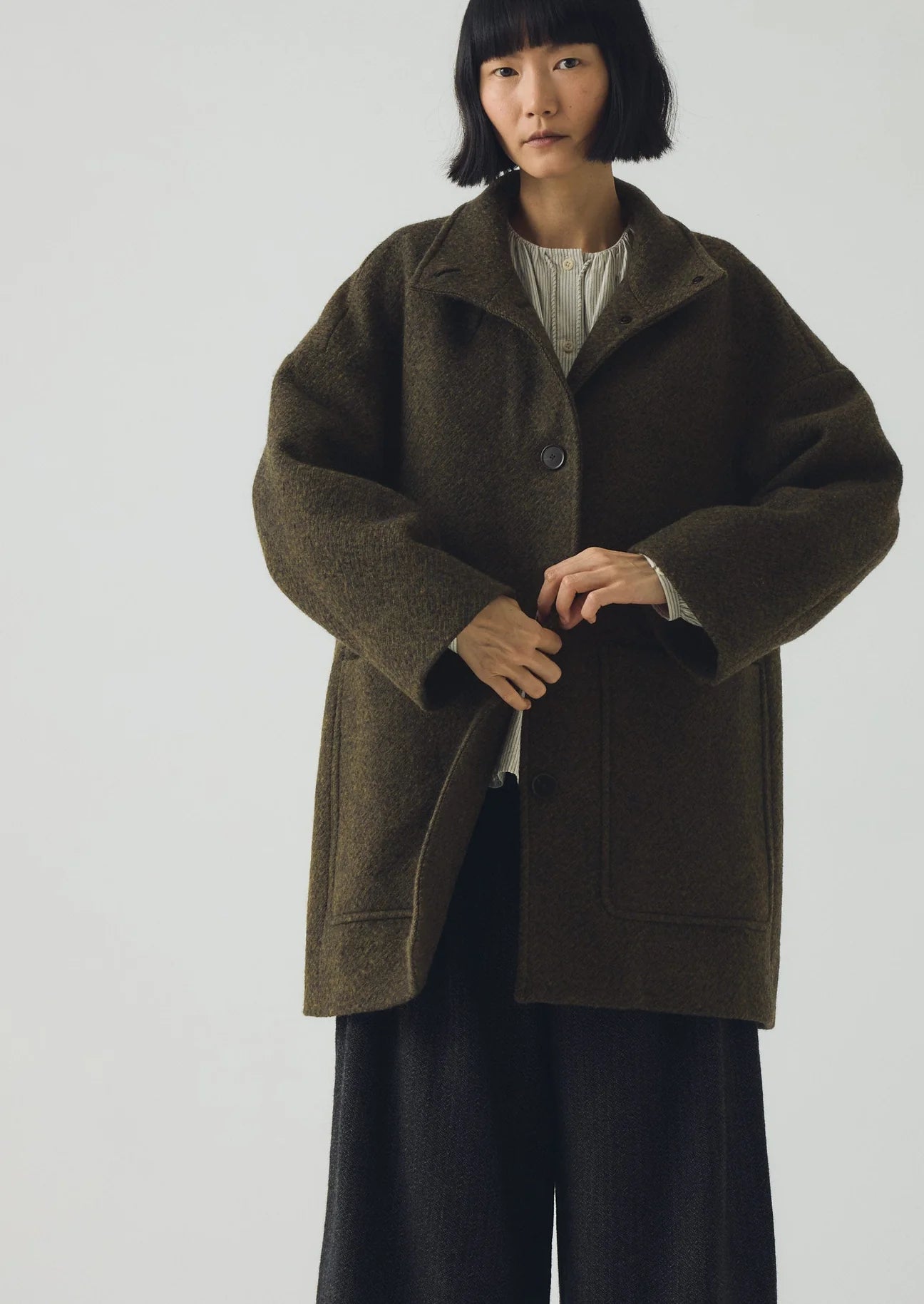 Person wearing a dark green coat on a plain background