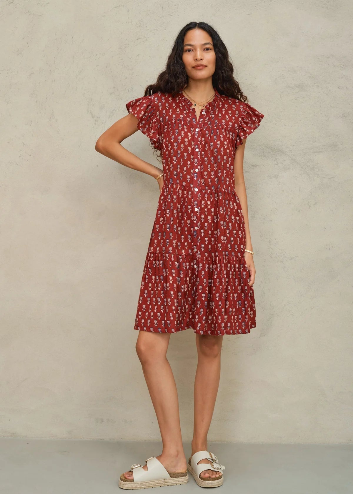 Woman wearing a red patterned dress against a neutral background