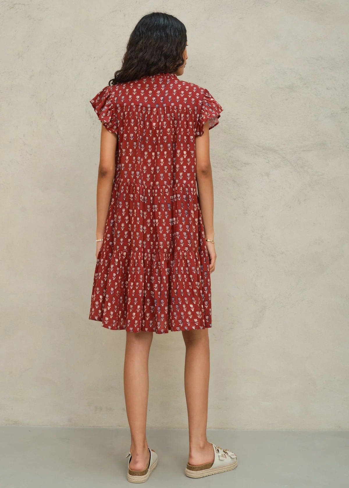 Woman wearing a red patterned dress against a beige background