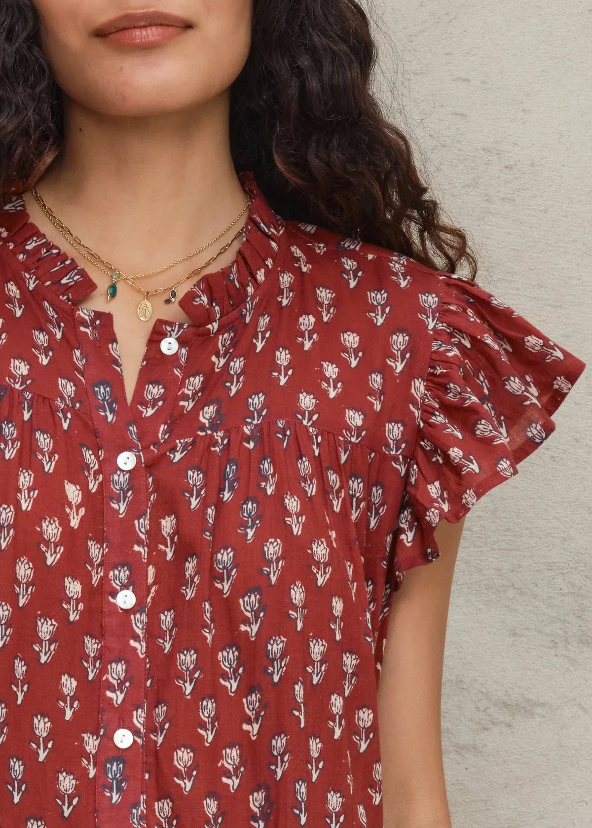 Woman wearing a red floral blouse against a neutral background