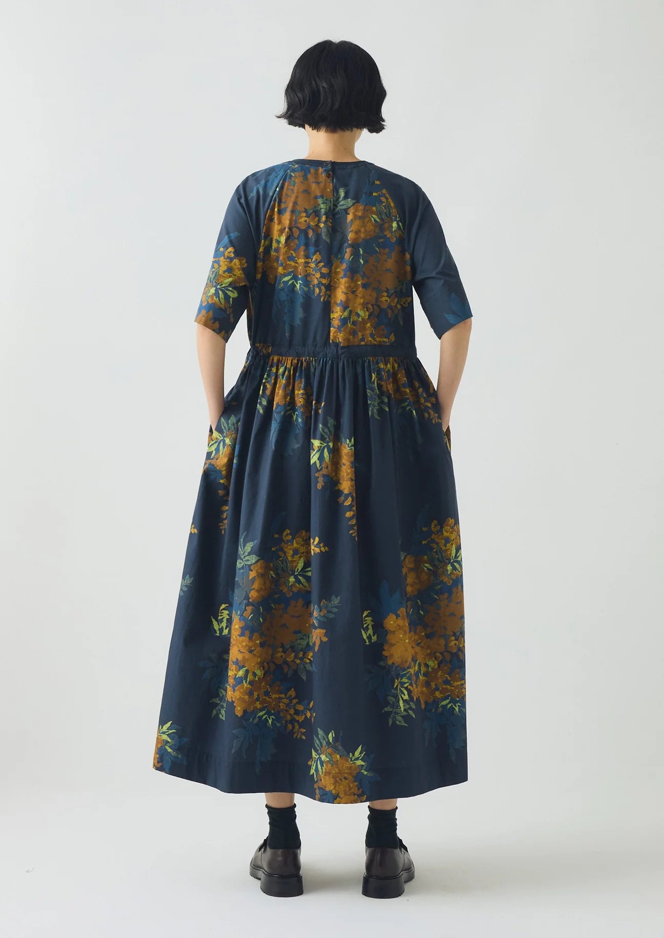 Person wearing a long floral dress with a neutral background
