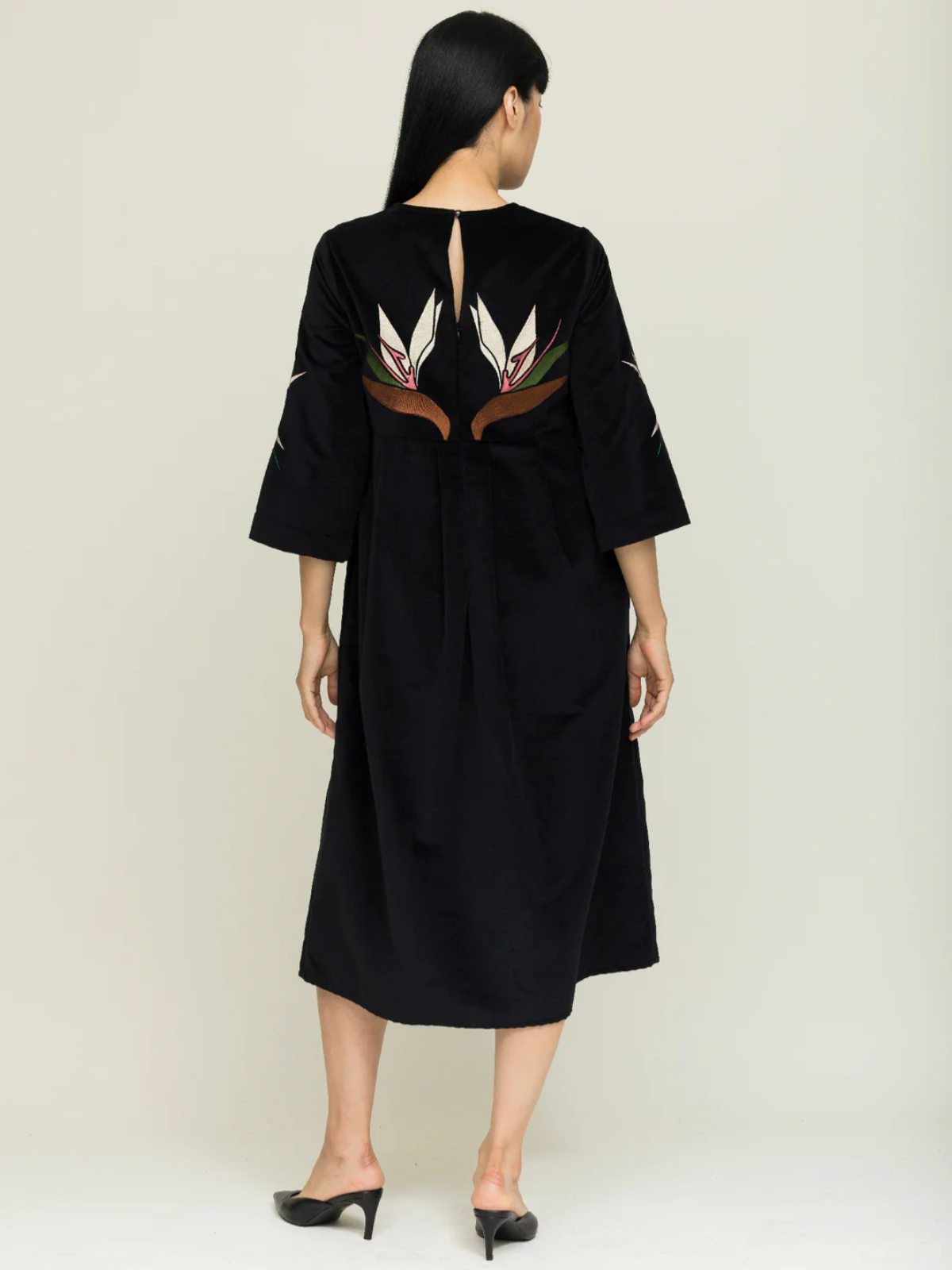 Black dress with feather embroidery on a plain background