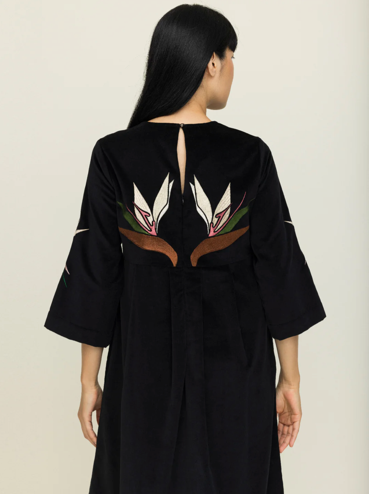 Black dress with floral embroidery on a plain background