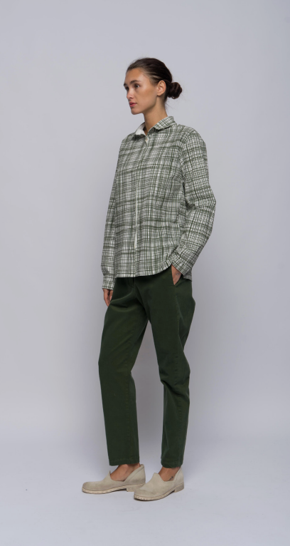 Model shown against a light grey background wearing green pants and an olive plaid collared, button-down shirt.