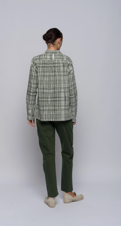 Model's back shown against a light grey background wearing green pants and an olive plaid collared, button-down shirt.