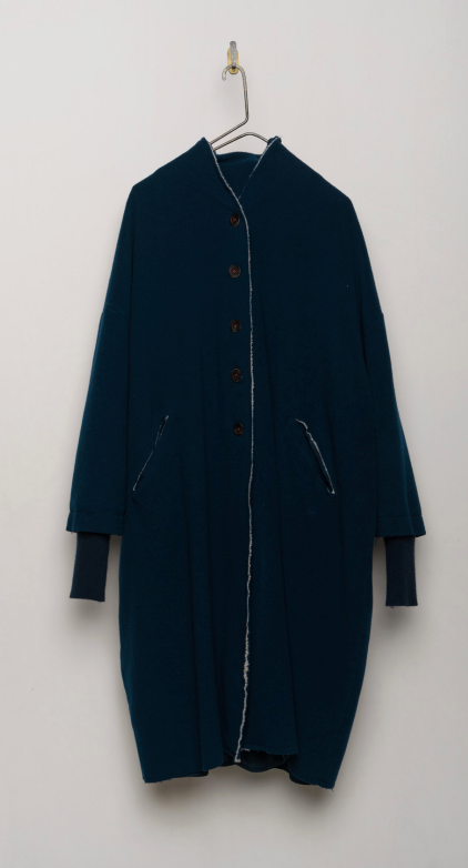 Wool and cashmere blend coat in inky blue hanging on a hook. Features dropped shoulders, front pockets and cashmere knit cuffs.