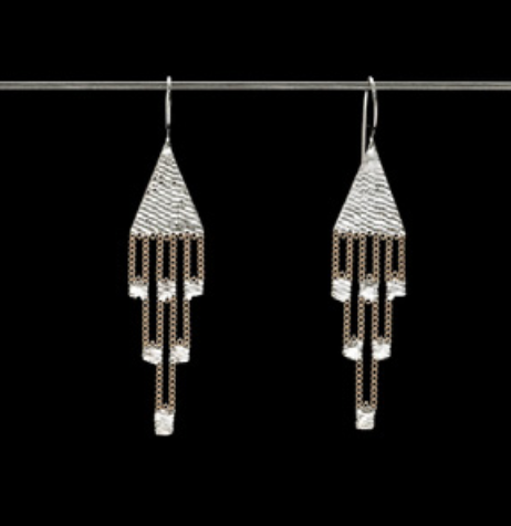 A pair of silver-toned dangle earrings with textured geometric tops and cascading chain-like drops, shown hanging against a solid black background.