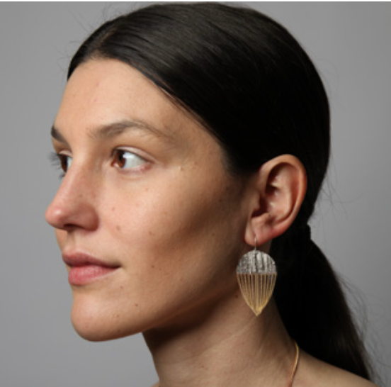 A model shown with silver and brass chain earrings in a parachute-shape.