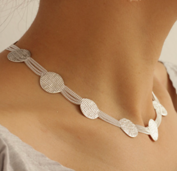 A model wearing a sterling silver necklace with a pattern of silver circles and chains.