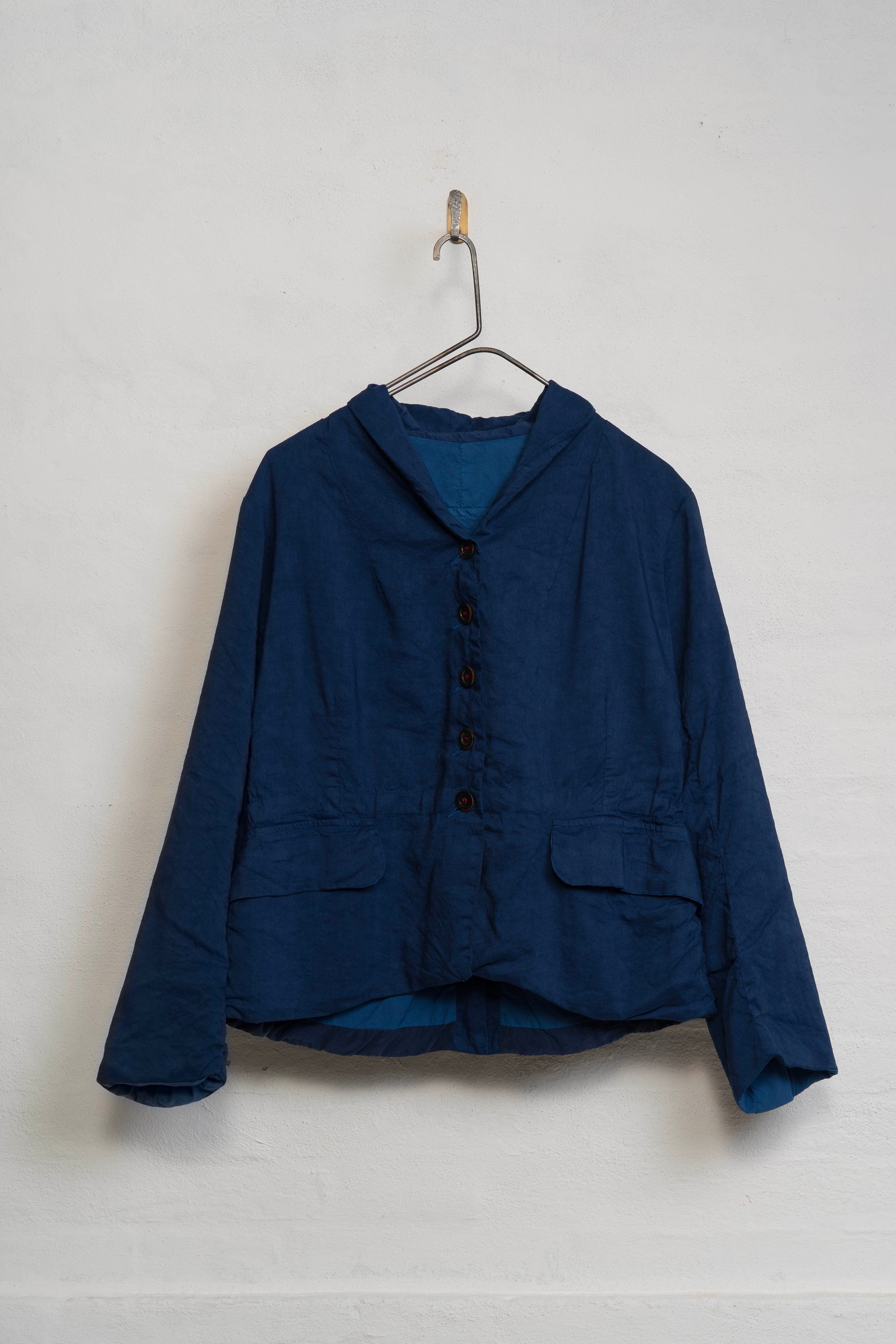 Blue jacket on a hanger against a white wall
