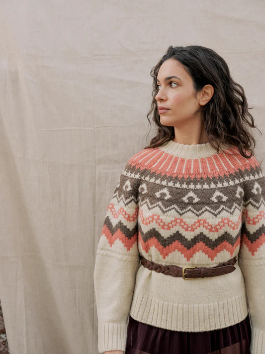 Woman wearing a patterned sweater against a plain background