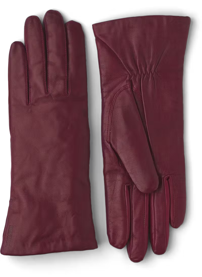 A pair of dark red womens leather gloves on a black background