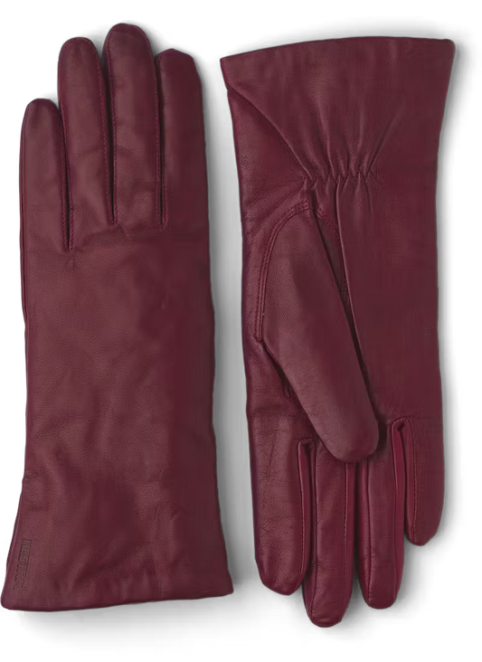 A pair of dark red womens leather gloves on a black background