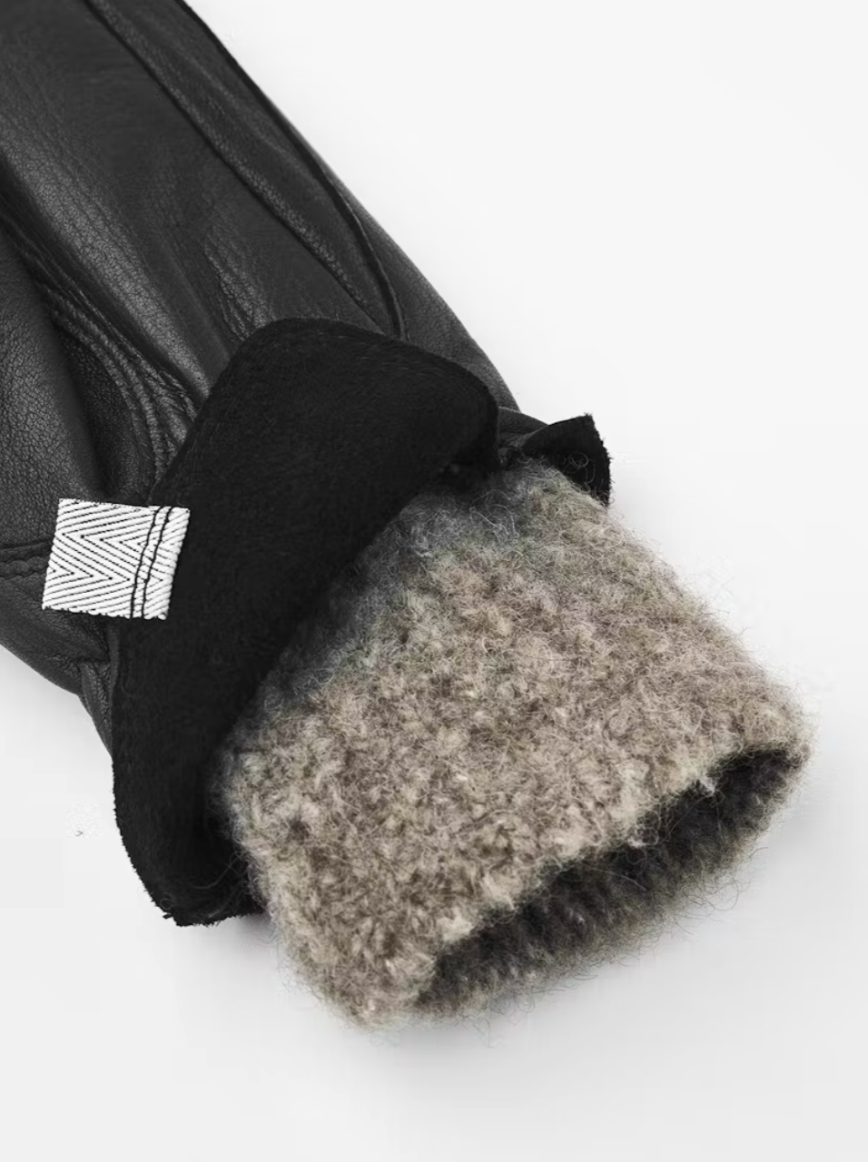 Close-up of a black leather glove with gray fur lining on a white background