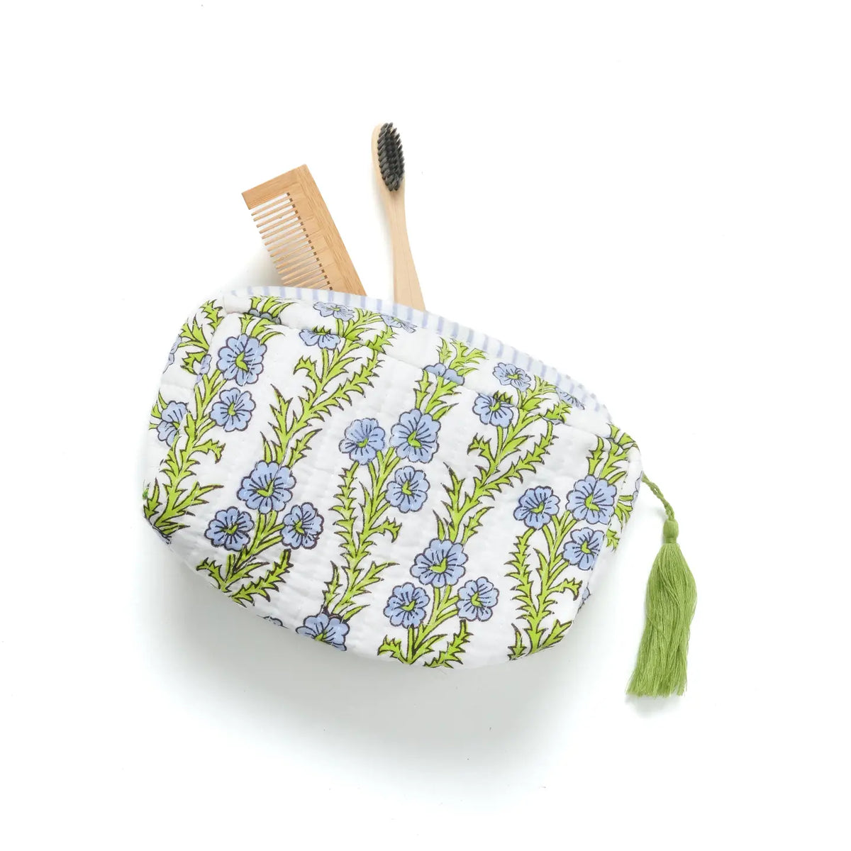 Floral-patterned pouch with a tassel, a wooden comb, and a bamboo toothbrush on a white background