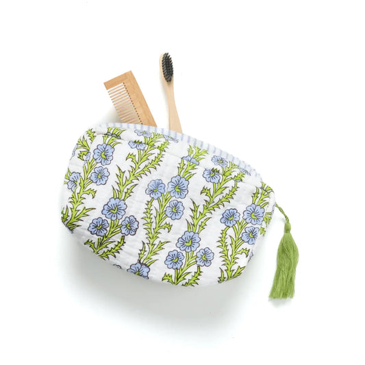 Floral-patterned pouch with a tassel, a wooden comb, and a bamboo toothbrush on a white background