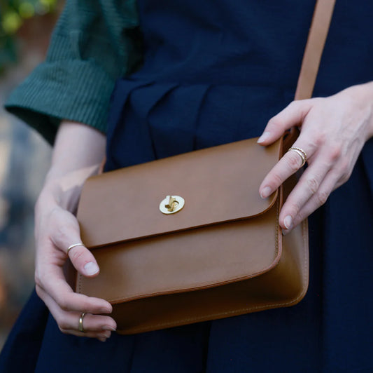 Brown leather handbag held by a person with a blurred background