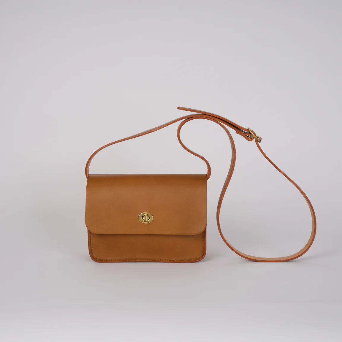 Brown leather handbag with a strap on a light gray background