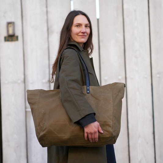 Woman holding a large brown tote bag against a wooden background