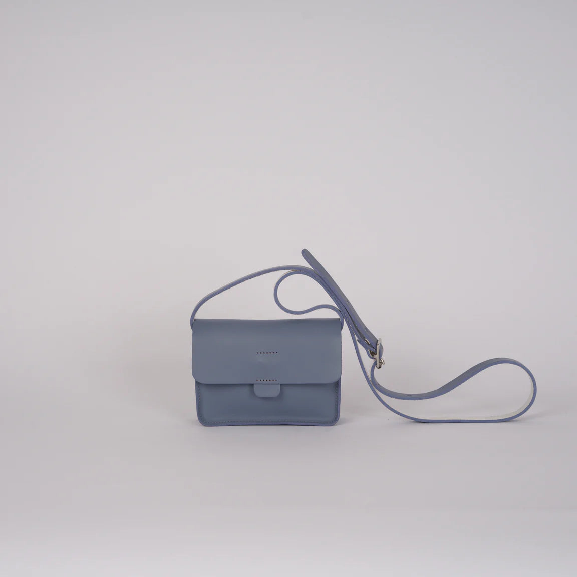 Blue handbag with a strap on a light gray background